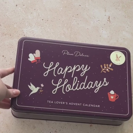 A video unboxing the Tea Lover's Advent Calendar. A purple tin with "Happy Holidays" on the front and a key sheet, teas, and a how to use guide inside.