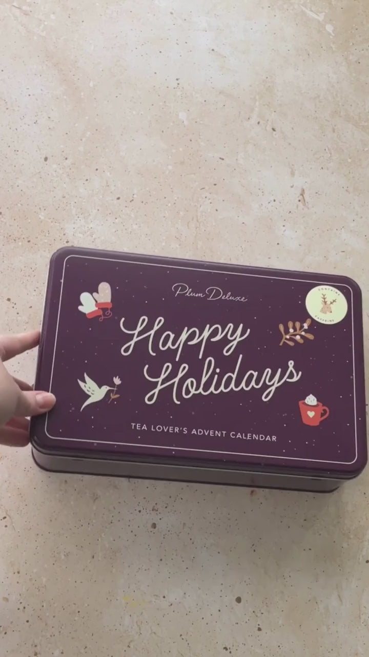 A video unboxing the Tea Lover's Advent Calendar. A purple tin with "Happy Holidays" on the front and a key sheet, teas, and a how to use guide inside.
